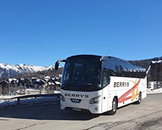 A Berrys Coach with snowy hills in the background